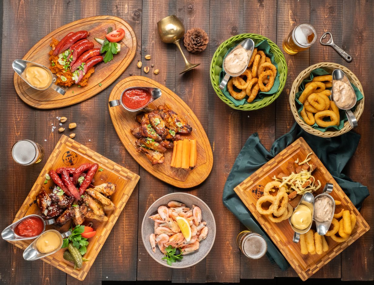 Пивные закуски на досках: крылья, колбаски, кольца кальмара, креветки, гренки с соусами